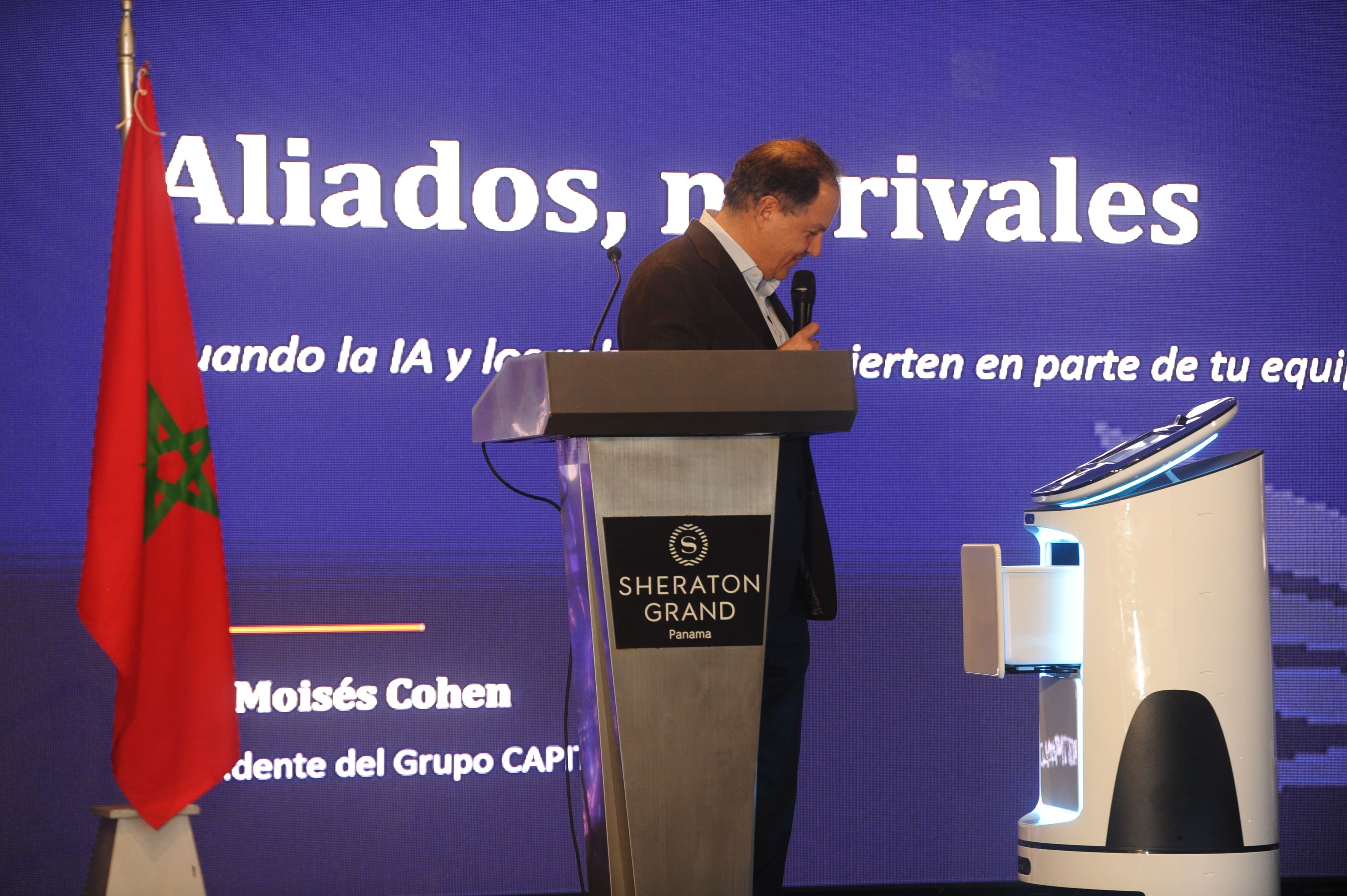 Moisés Cohen en el podio del Sheraton Grand Panamá con robot Capital Robots y bandera de Marruecos — Foro Empresarial WISS Latam 2026