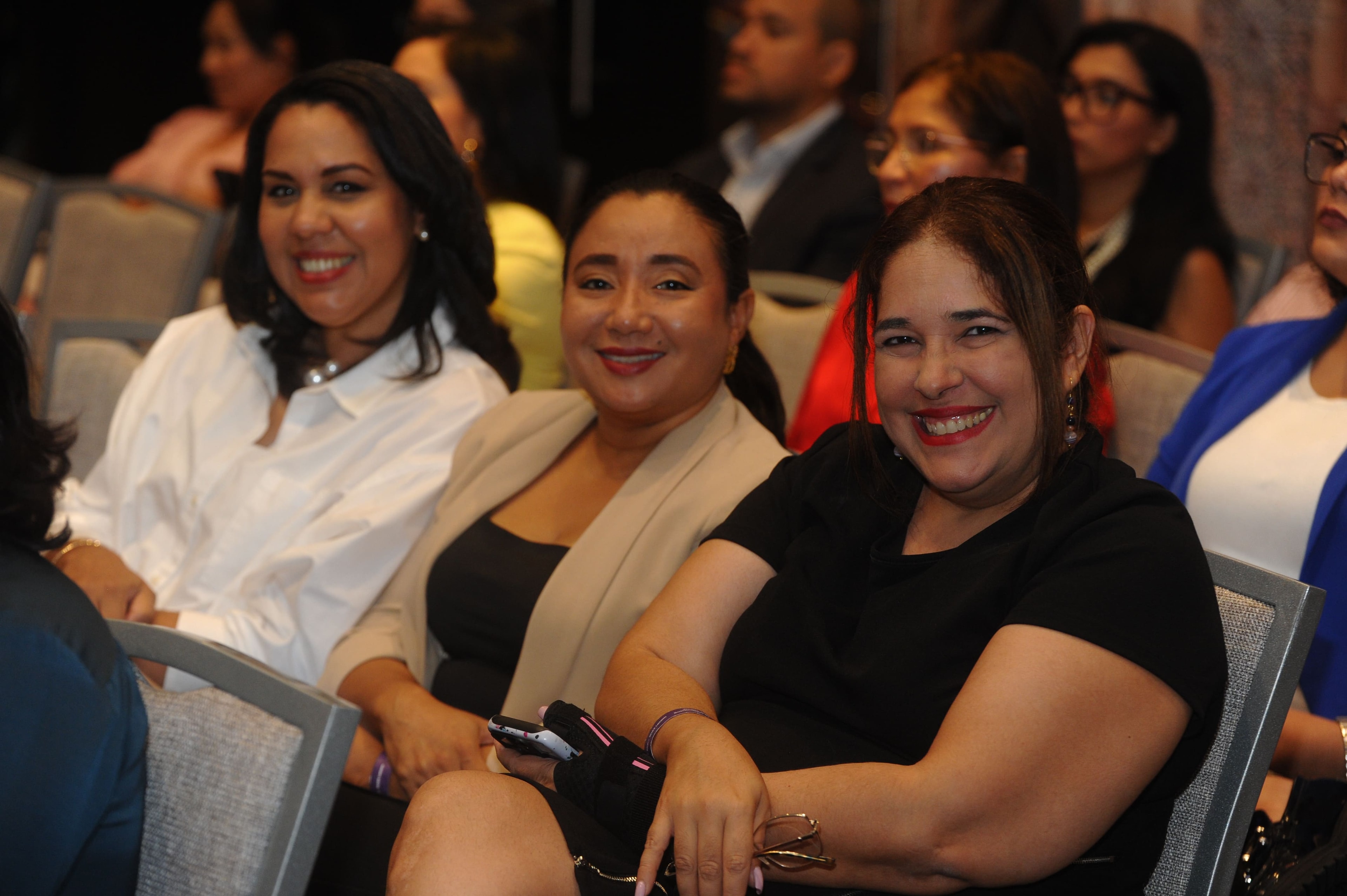 Tres asistentes sonriendo en el salón del Foro Empresarial WISS Latam 2026