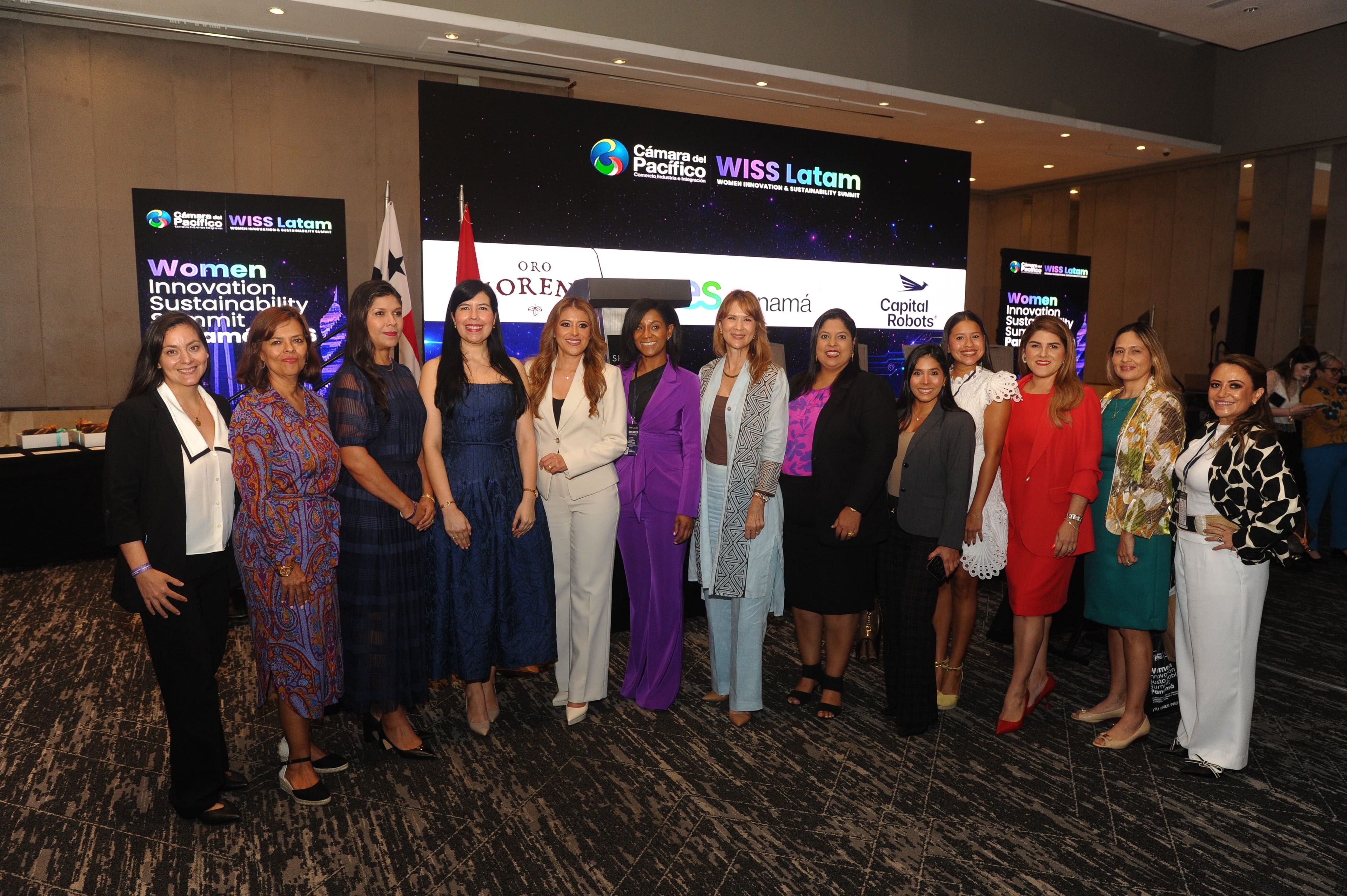 Gran grupo de mujeres posando y saludando frente a pantalla WISS Latam con logos Sony, KB4U y Varela Hermanos — Foro Empresarial 27 Ago 2026