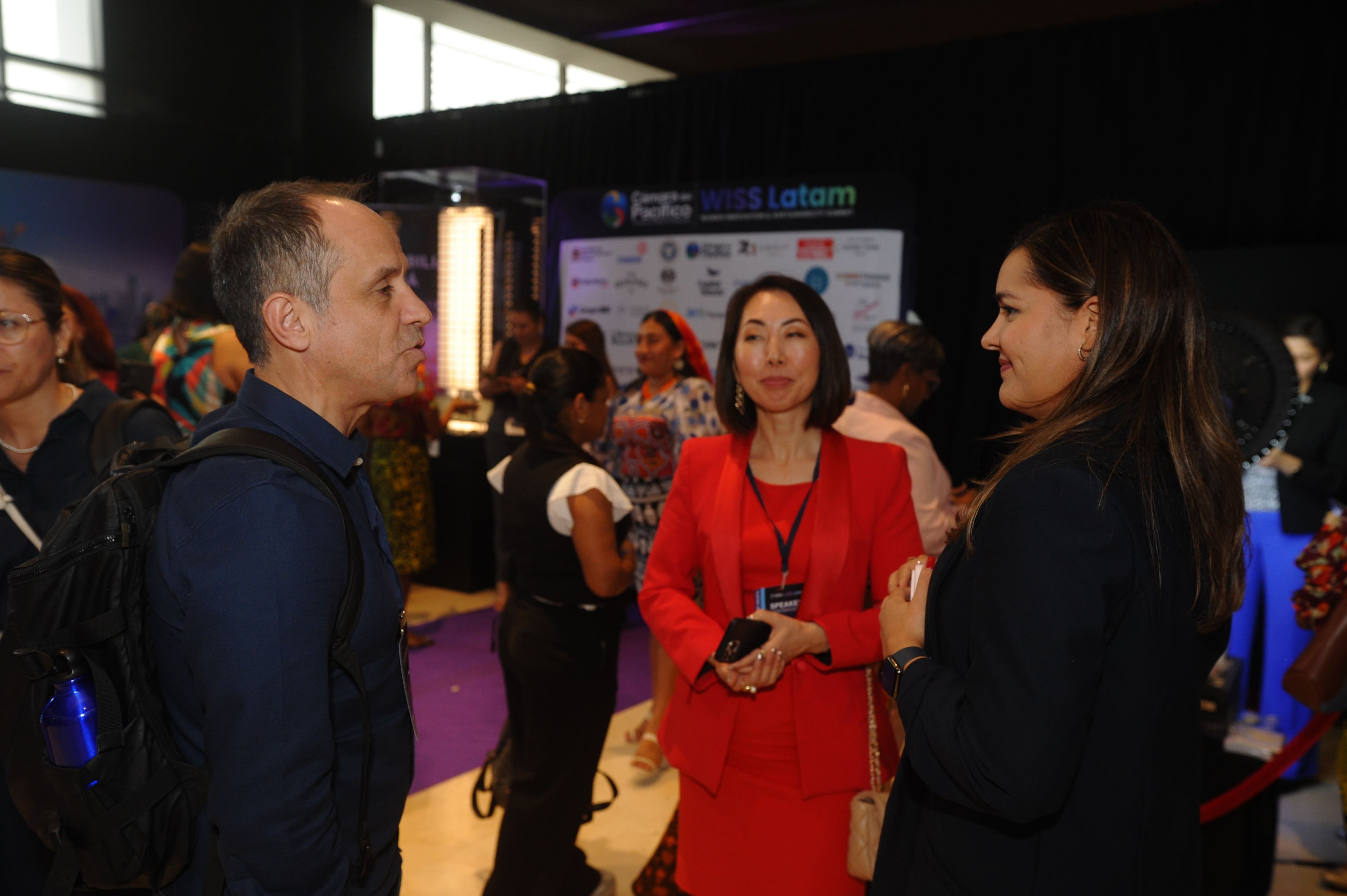 Dos asistentes sonriendo junto al robot de Capital Robots en el lobby del Foro Empresarial WISS Latam 2026