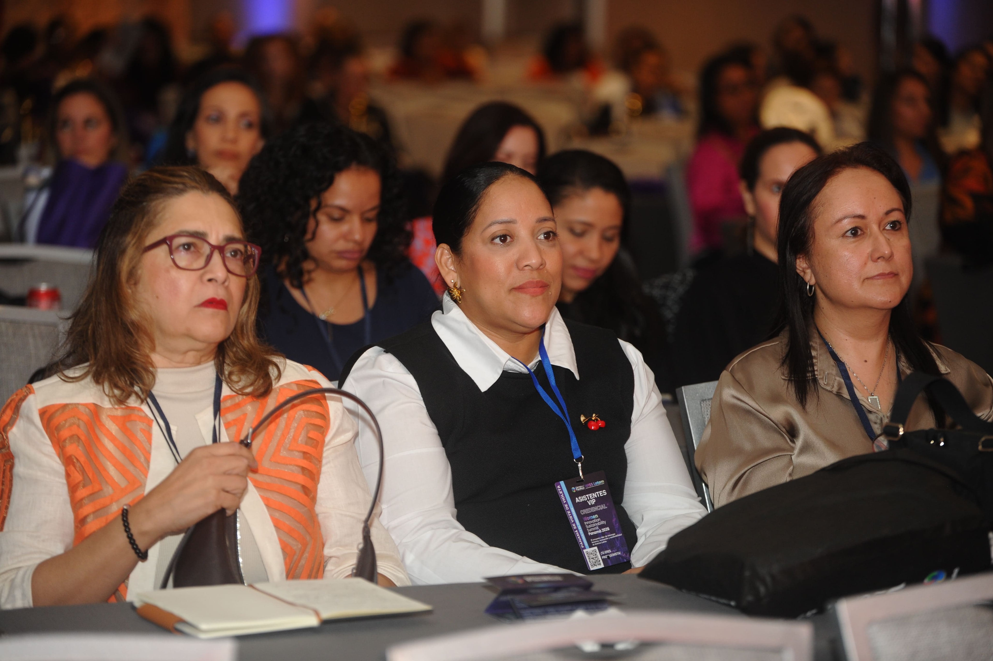 Tres asistentes VIP sentadas en el auditorio del Foro Empresarial WISS Latam 27 Ago 2026 — credencial WISS visible