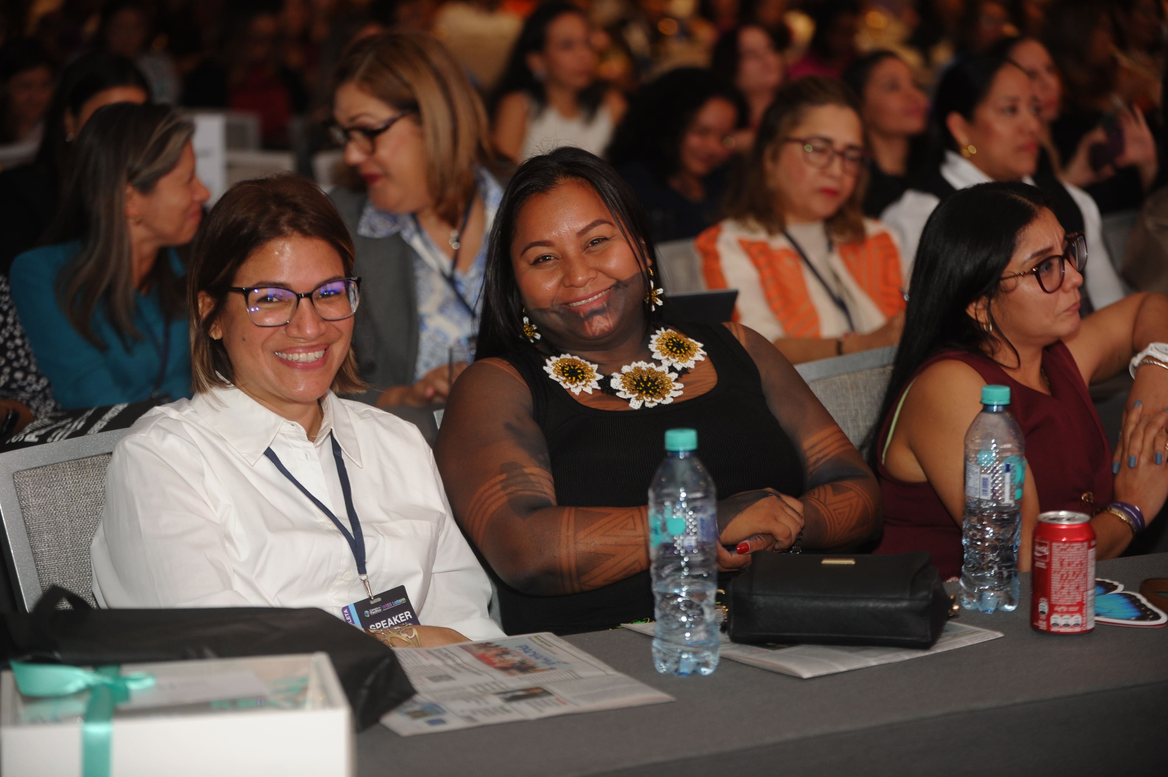 Dos asistentes sonriendo en el auditorio del Foro Empresarial WISS Latam 27 Ago 2026 — credencial SPEAKER visible