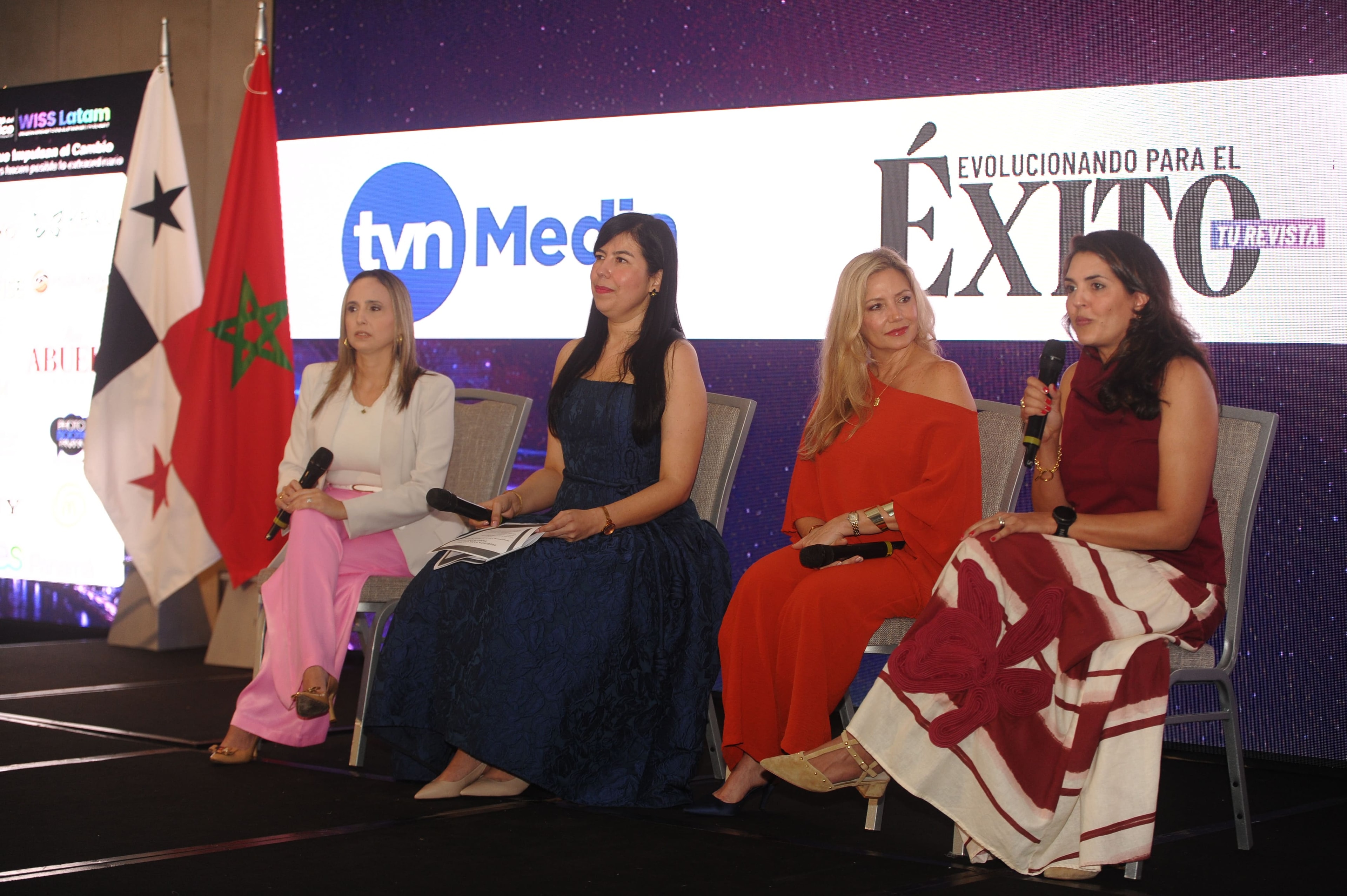 Panel de pie en el escenario con pantalla WISS Latam — Diana Olaya, moderadora en azul, Marcela Martínez y Nicole Orillac — Foro 27 Ago 2026