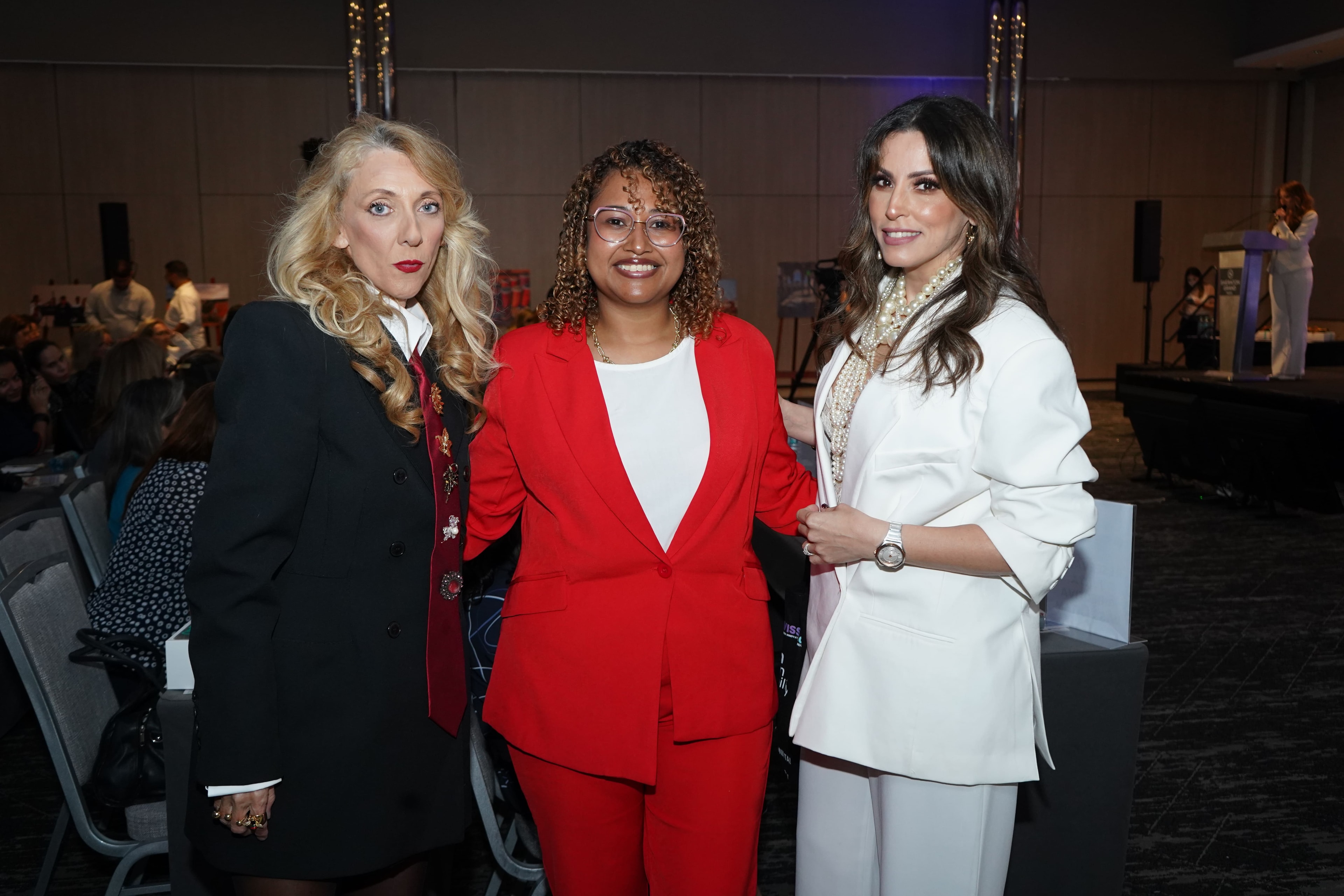 Tres mujeres posando en el salón del Foro Empresarial WISS Latam 27 Ago 2026 — Gaby Gnazzo de negro, mujer de rojo y panelista de blanco