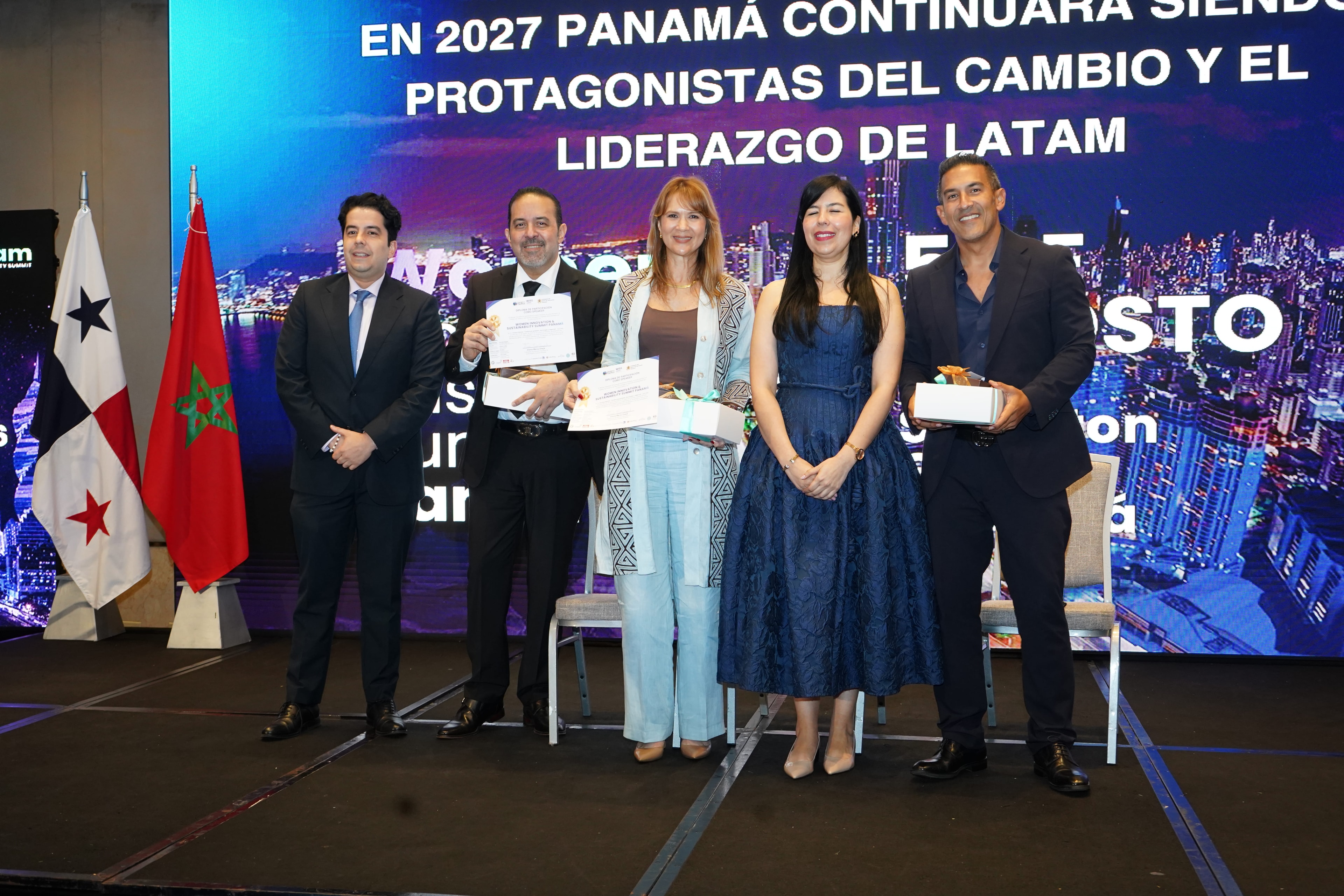 Cinco personas de pie con reconocimientos frente a pantalla "En 2027 Panamá continuará siendo protagonistas del cambio" — banderas de Panamá y Marruecos — Foro 27 Ago 2026