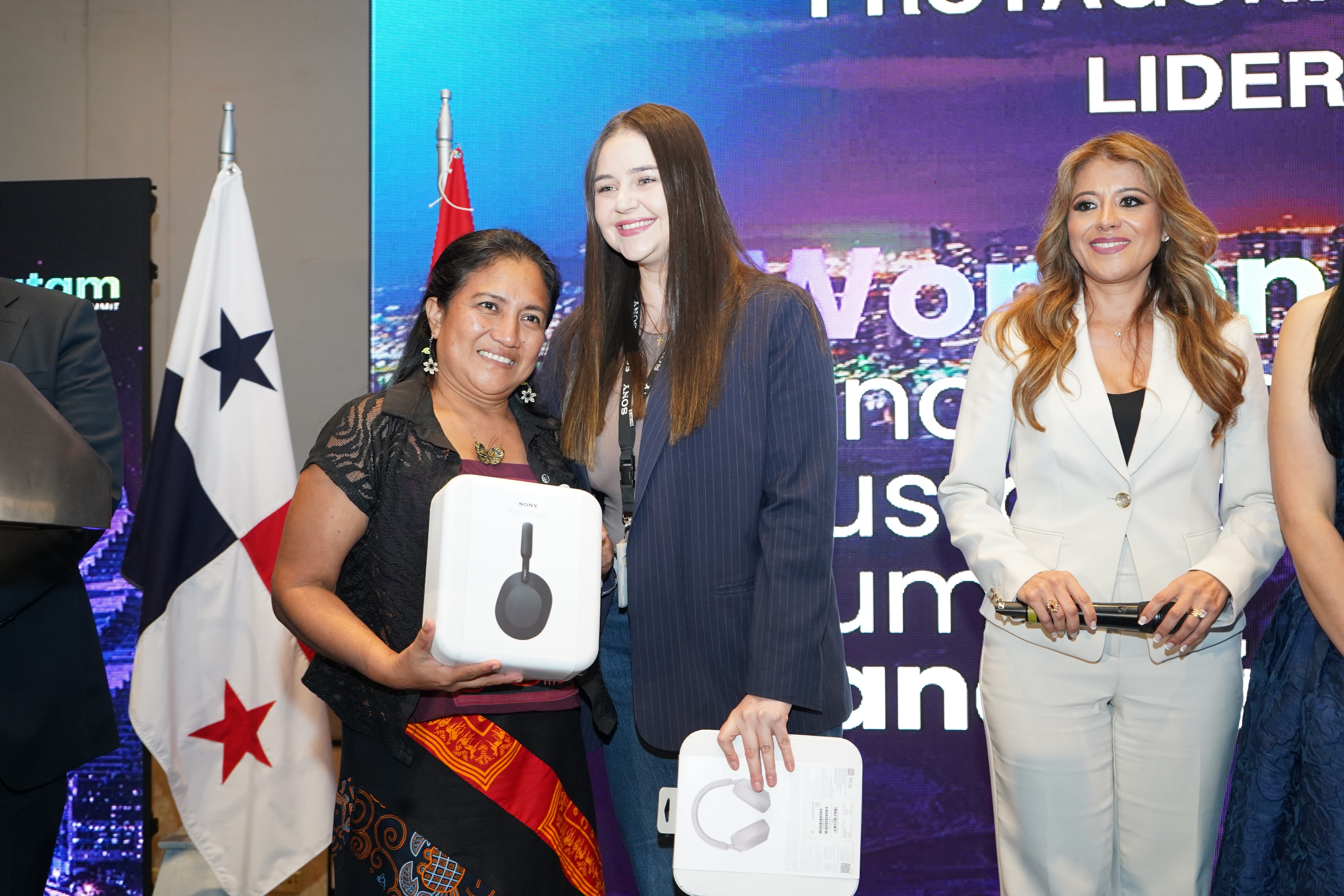Tres mujeres posando — mujer indígena con audífonos Sony, joven con blazer azul marino y mujer de traje blanco — entrega de premios Sony — Foro 27 Ago 2026