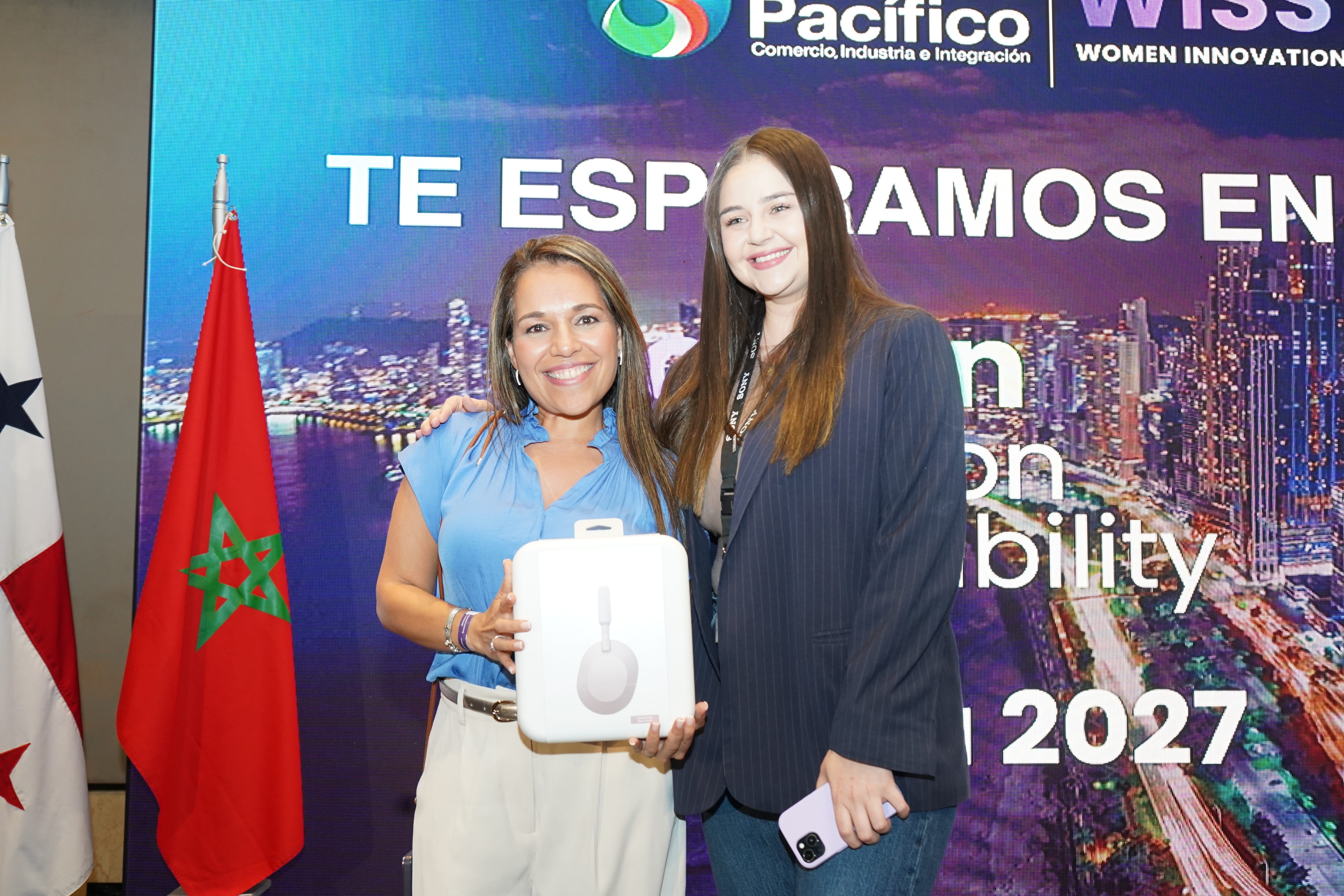 Dos mujeres posando con caja de audífonos Sony frente a banner "Te esperamos en 2027" — banderas de Panamá y Marruecos — Foro Empresarial WISS Latam 27 Ago 2026