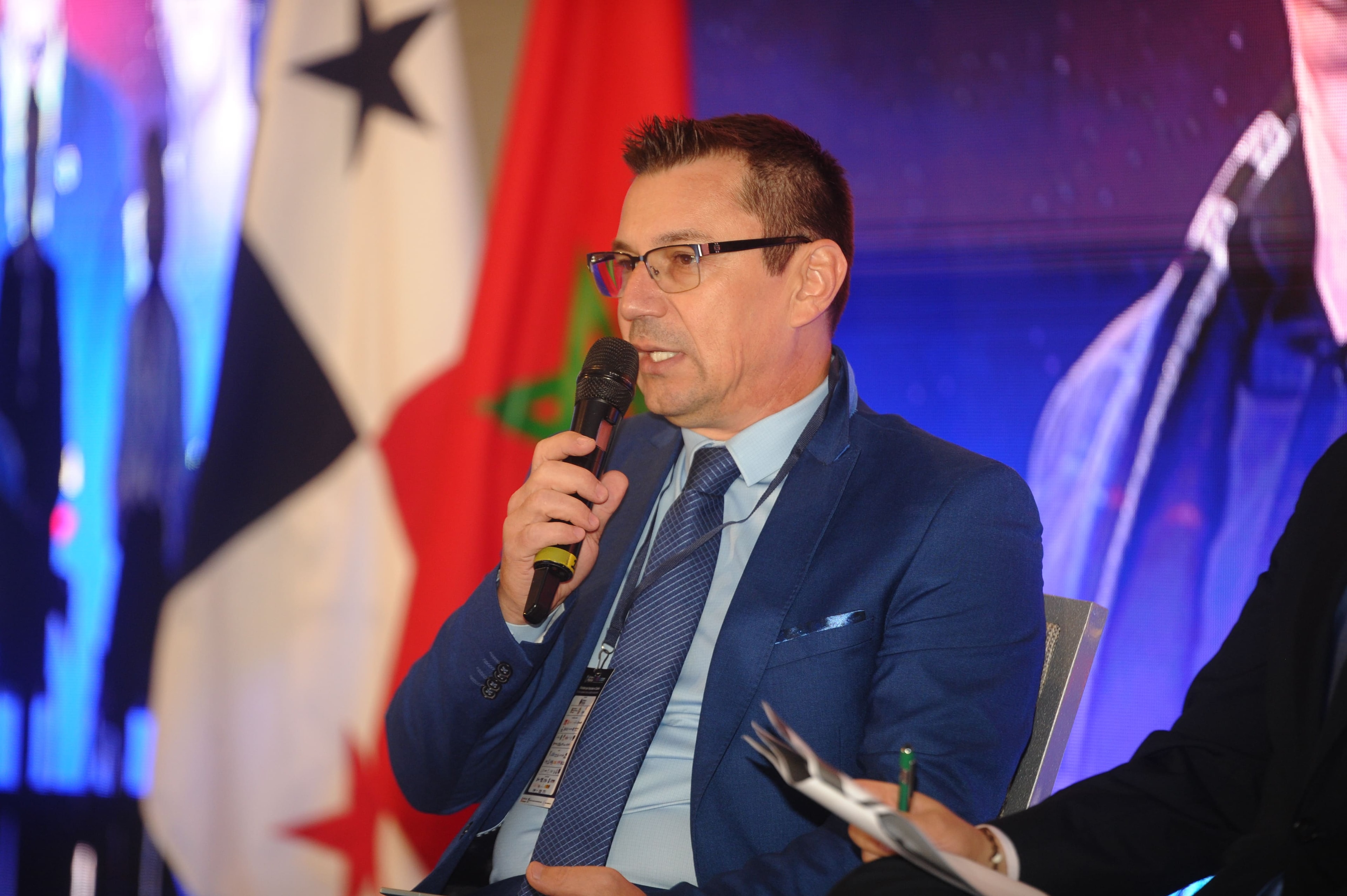 Panelista con micrófono frente a banderas de Panamá y Marruecos — WISS Latam 2026